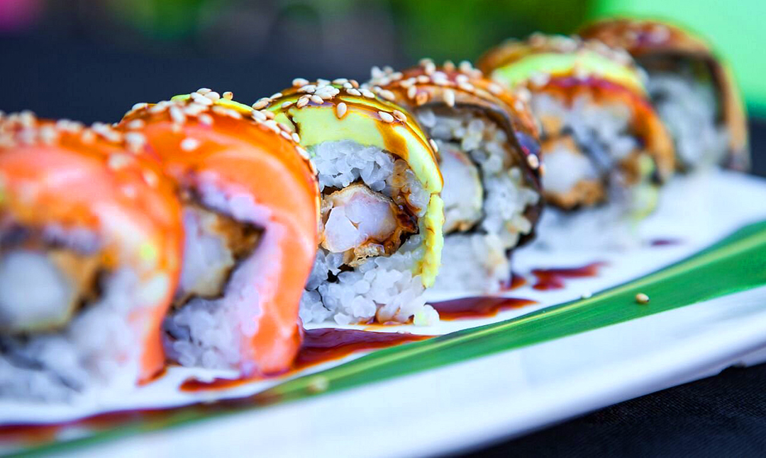 A table of plated sushi rolls and cocktails.